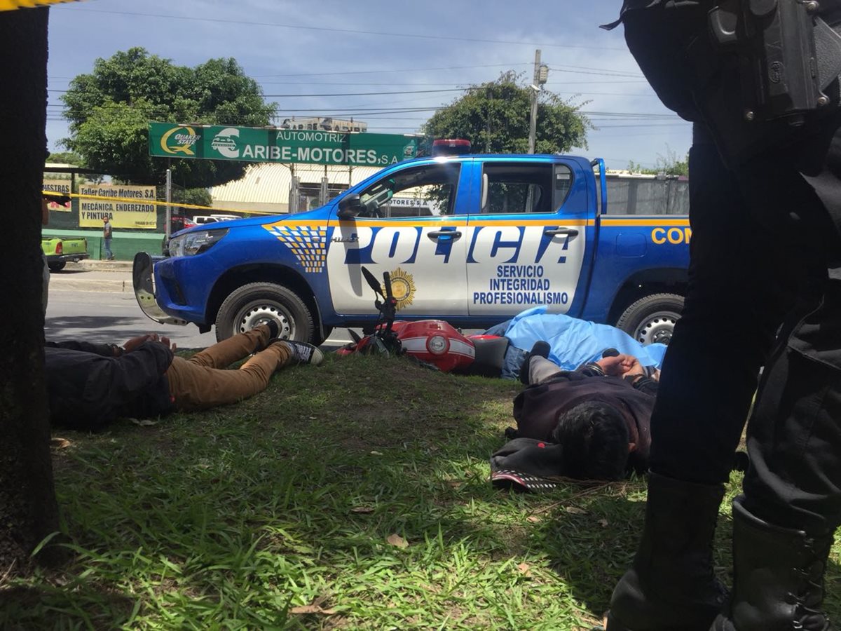 Policía resguarda a los dos supuestos menores capturados; al fondo, la moto y la persona fallecida. (Foto: Cortesía)