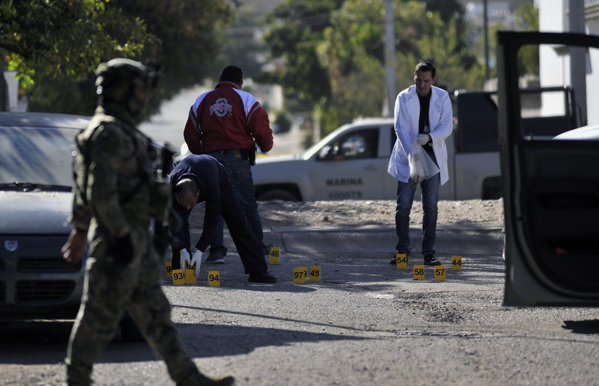 Forenses mexicanos recaban evidencias en el lugar del enfrentamiento armado. (Foto Prensa Libre: AFP)