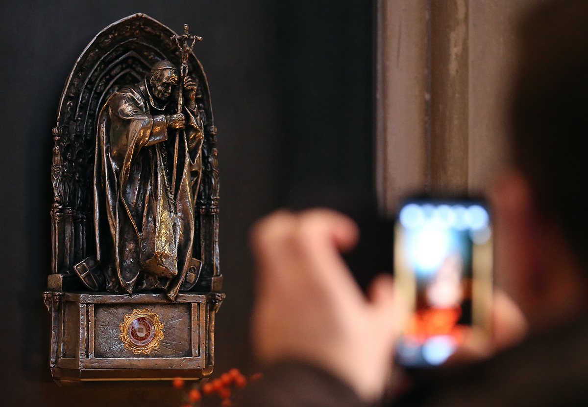 Un turista toma una fotografía a la reliquia de Juan Pablo Segundo, de cuyo interior fue extraído el trozo de tela en Colonia. (Foto Prensa Libre: AP).