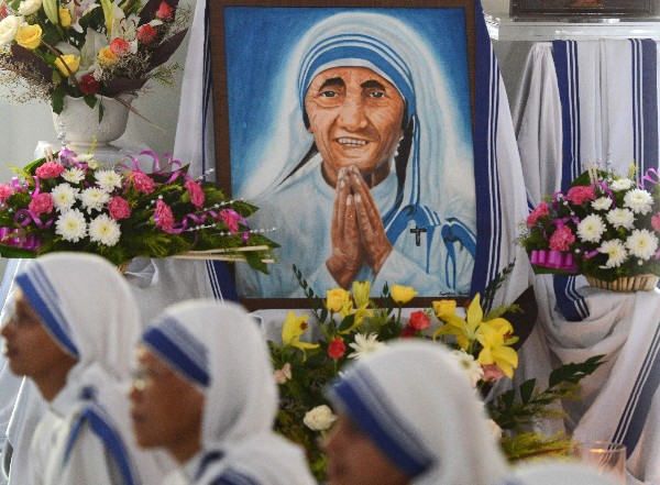 Fieles y monjas indias colocan flores a un retrato de la Madre Teresa en Siliguri. (Foto Prensa Libre: AFP).