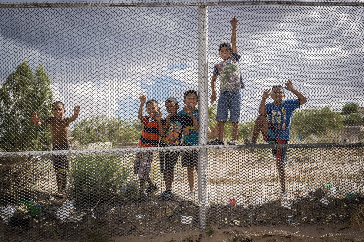 Niños de Anapra, México, saludan y piden dólares a los residentes de Sunland Park, Nuevo México, EE. UU., en la vieja valla que separa ambas ciudades. (Foto Prensa Libre: EFE).