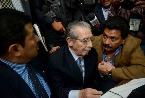 Uno de los abogados tranquiliza al ex jefe de Estado, Efraín Ríos Montt durante la lectura de la sentencia. (Foto Prensa Libre: AFP)