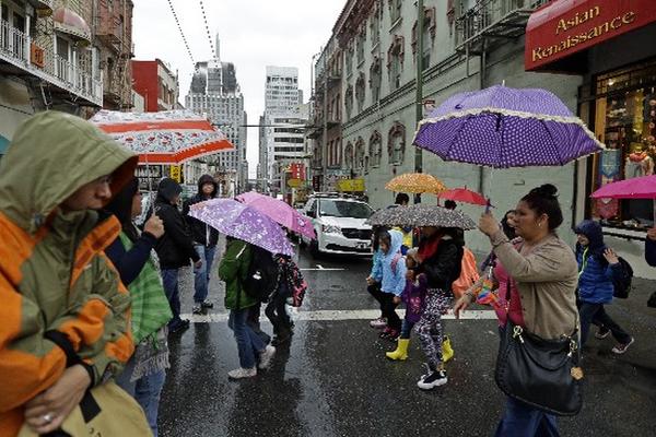Los peatones se cubren de la lluvia en el barrio de Chinatown de San Francisco. Los vuelos fueron retrasados en San Francisco. (Foto Prensa Libre:AP)