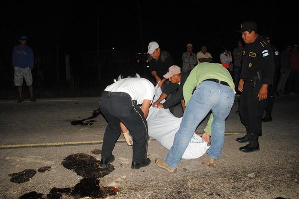 Autoridades y vecinos cubren cadáver de motociclista, en Poptún, Petén. (Foto Prensa Libre: Rigoberto Escobar)<br _mce_bogus="1"/>