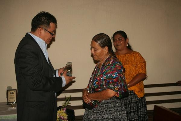 Juan Pablo Morán López, integrante de la cofradía de Santo Domingo de Guzmán, entrega un reconocimiento a una de las homenajeadas. (Foto Prensa Libre: Ángel Tax)