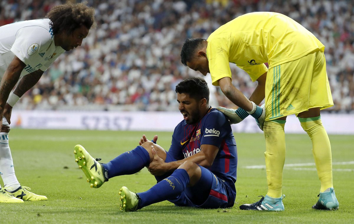 El brasileño Marcelo y el portero Keylor Navas, del Real Madrid, consuelan a Luis Suárez quien se queja de la lesión en la rodilla derecha. (Foto Prensa Libre: EFE)
