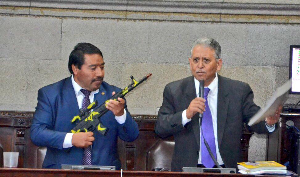 El diputado Pedro Méndez Carreto, sostiene un fusil de juguete mientras su colega Ovidio Monzón, discute sobre la necesidad de asignar más presupuesto a la Educación y no al Ejército. (Foto Prensa Libre: José Castro)