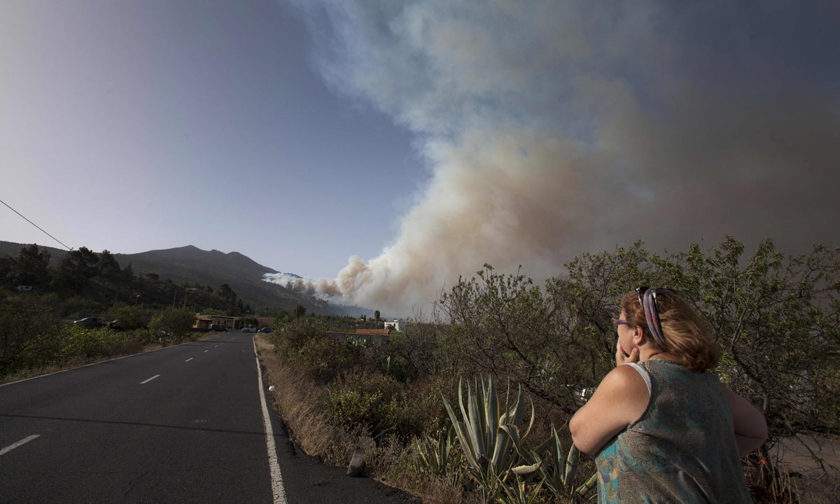 Una mujer observa la magnitud del incendio en La Palma, Canarias, España, en donde perdió la vida un agente forestal. (Foto Prensa Libre: AFP).