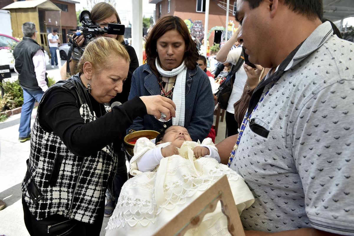 Una bebé recibe la bendición de su madrina Enriqueta Vargas (i), durante una celebración a la Santa Muerte en Tultitlan, Mexico. (Foto Prensa Libre: AFP).