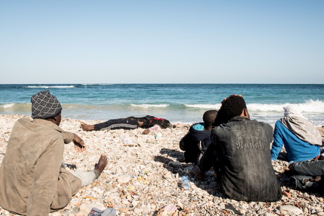 Inmigrantes sobrevivientes del naufragio observa los cuerpos de los ahogados en Harcha, Libia. (Foto Prensa Libre:AFP)
