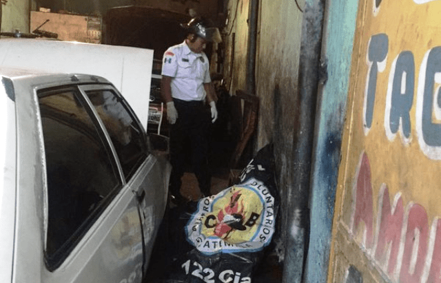 Un Bombero Voluntario observa el cuerpo de Avilés, el cual quedó en el interior de su taller. (Foto Prensa Libre: Bomberos Voluntarios)
