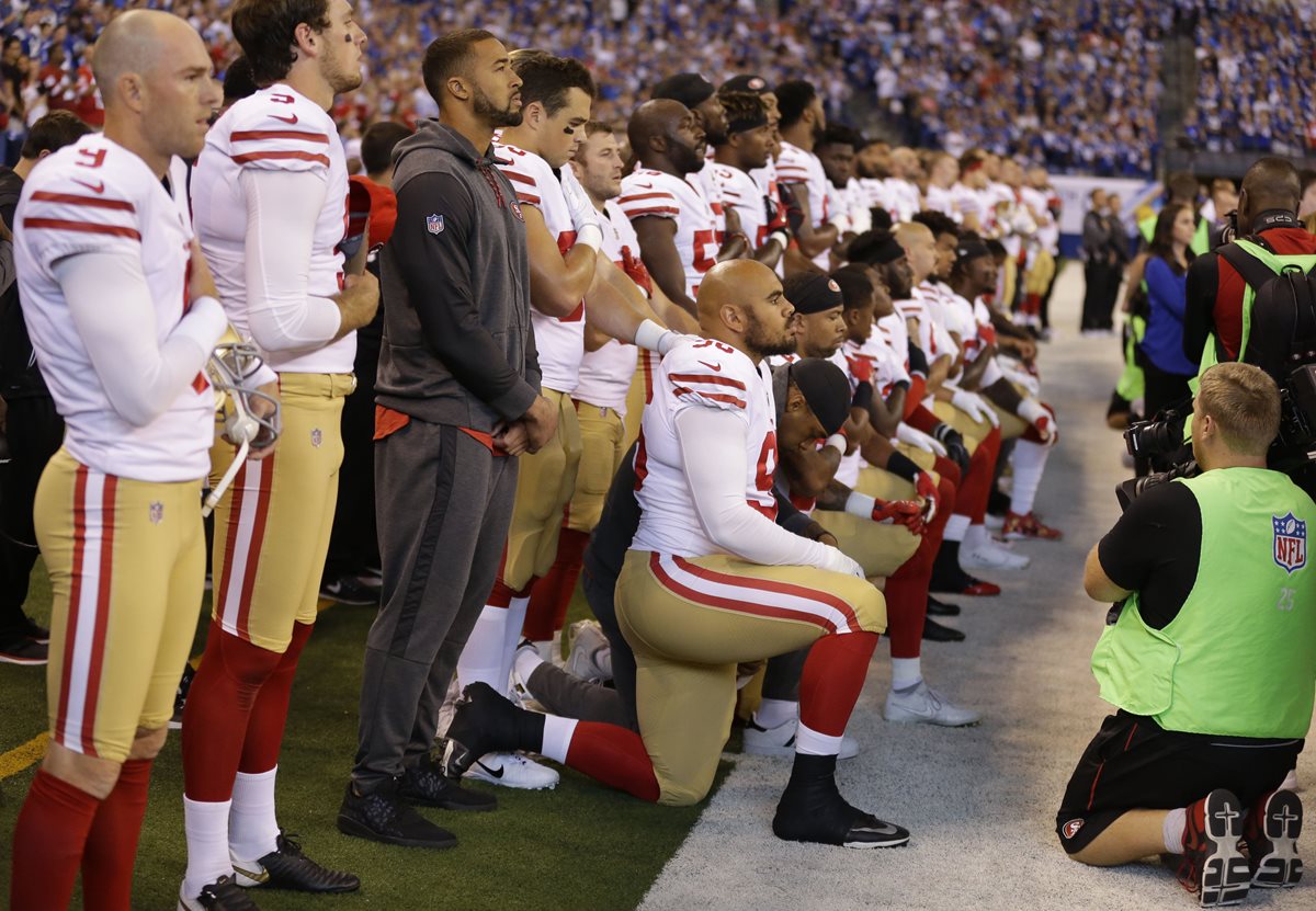 Jugadores de los 49ers se arrodillan durante el himno nacional, lo que motivó la protesta de Pence. (Foto Prensa Libre: AP)