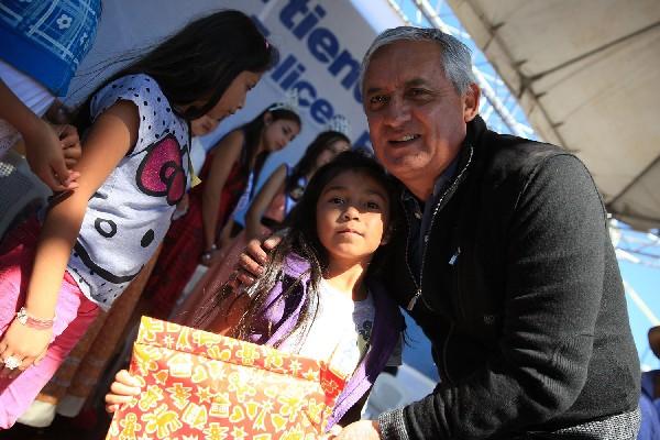 El presidente Otto Pérez Molina  entregará viviendas en San Marcos a damnificados por terremoto. En la gráfica entrega regalos a niños en vísperas de Navidad.