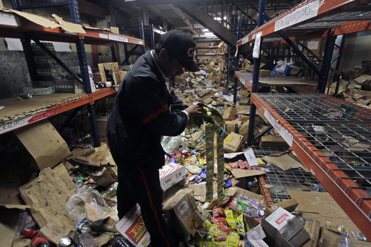 Un guardia de seguridad muestra las mercancías del supermercado después de los saqueos durante las protestas. (Foto Prensa Libre: AFP )