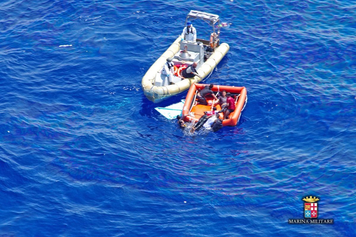 Miembros de la Marina rescatan a inmigrantes en medio del mar, la balsa de indocumentados está a punto de hundirse. (Foto Prensa Libre: AFP).