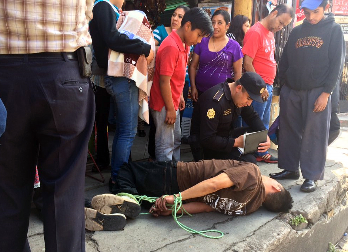 Un agente policial toma datos al hombre que fue atado por la turba. (Foto: Prensa LIbre: @stereo100xela)