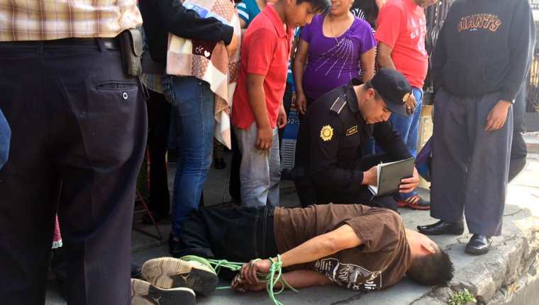 Un agente policial toma datos al hombre que fue atado por la turba. (Foto: Prensa LIbre: @stereo100xela)