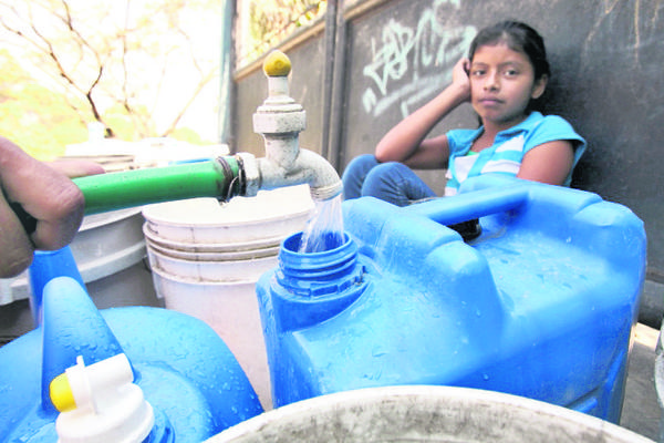 Vecinos de  la zona 6 llenan recipientes con agua que han comprado a camiones repartidores. (Foto Prensa Libre: Paulo Raquec)