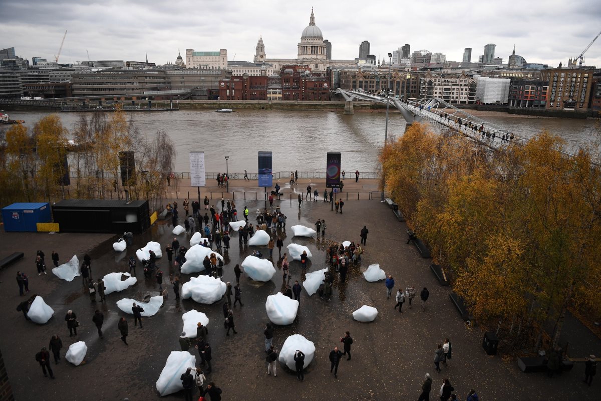 Visitantes observan la obre "Ice Watch" (lit.Reloj de hielo) de los artistas Minik Rosing y Olafur Eliasson a las afueras del Museo Nacional Británico de Arte Moderno en Londres, Reino Unido.Bloques de hielo de entre 1.5 y media y 6 toneladas de peso fueron traídos de Groenlandia para concienciar sobre los efectos del cambio climático. (Foto Prensa Libre: EFE)