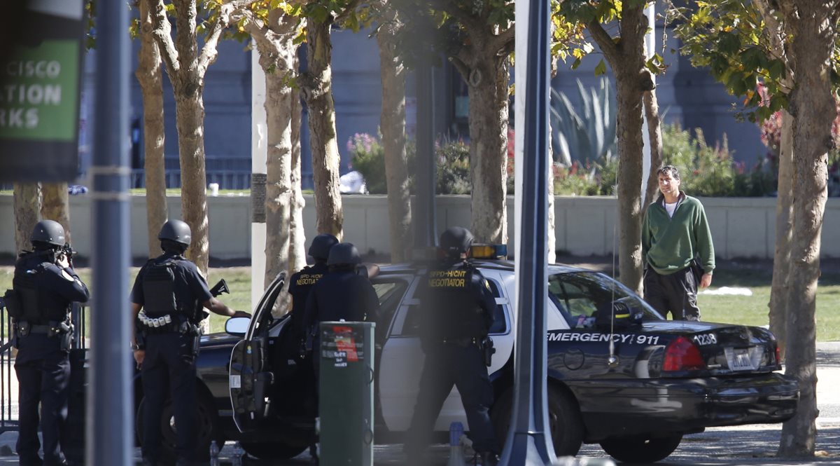 Oficiales de la Policía negocian con el hombre armado (de verde) en una plaza de San Francisco. (Foto Prensa Libre: AP).