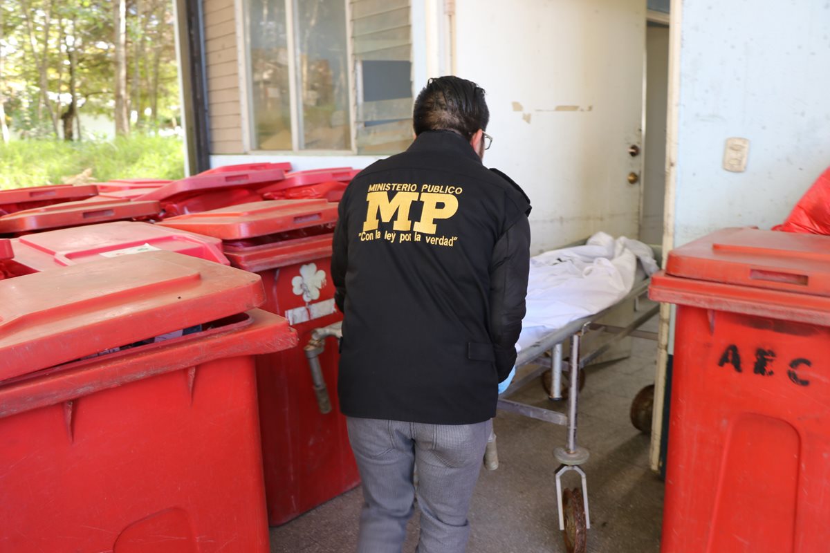 Un fiscal del Ministerio Público ingresa el cadáver de la mujer a la morgue del Instituto Nacional de Ciencias Forenses en San Marcos. (Foto Prensa Libre: Whitmer Barrera)