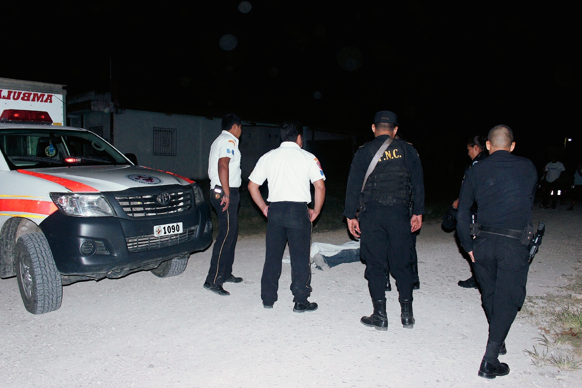 Socorristas y autoridades observan el cadáver de la persona que murió baleada, en San Benito, Petén. (Foto Prensa Libre: Rigoberto Escobar)