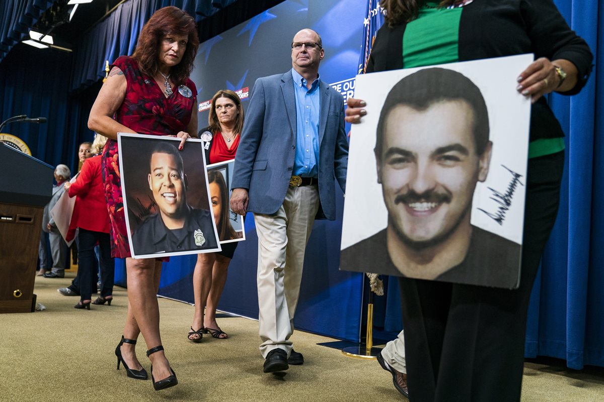 Un grupo de padres de familia portan retratos a sus seres queridos asesinados por inmigrantes criminales después de escuchar a Trump, pronunciarse sobre rl caso criminal. (EFE).