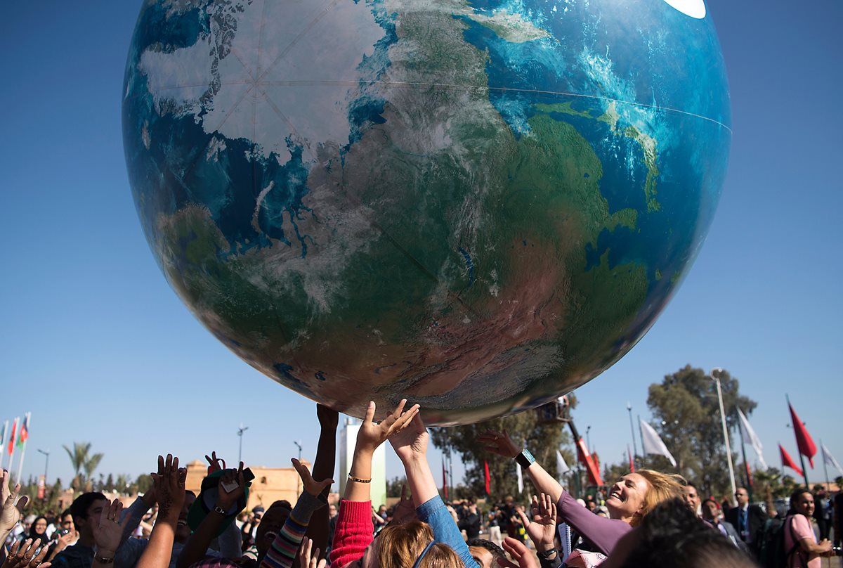 Integrantes de las delegaciones internacionales de la COP22 juegan con un globo aerostático gigante en Marrakech, Marruecos. (Foto Prensa Libre: AFP).