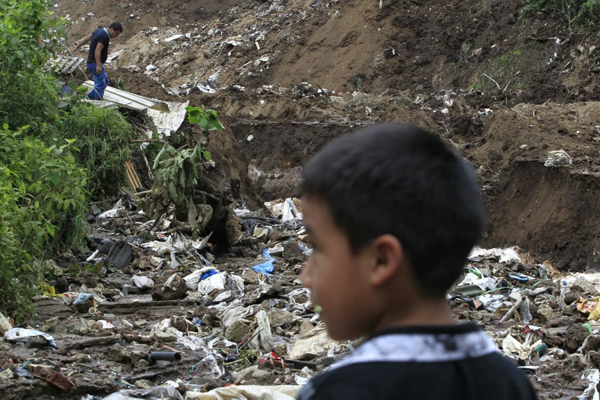 Niño observa la casa destruida de sus vecinos. Su vivienda está a cinco metros del lugar del derrumbe. (Foto Prensa Libre: Carlos Hernández)