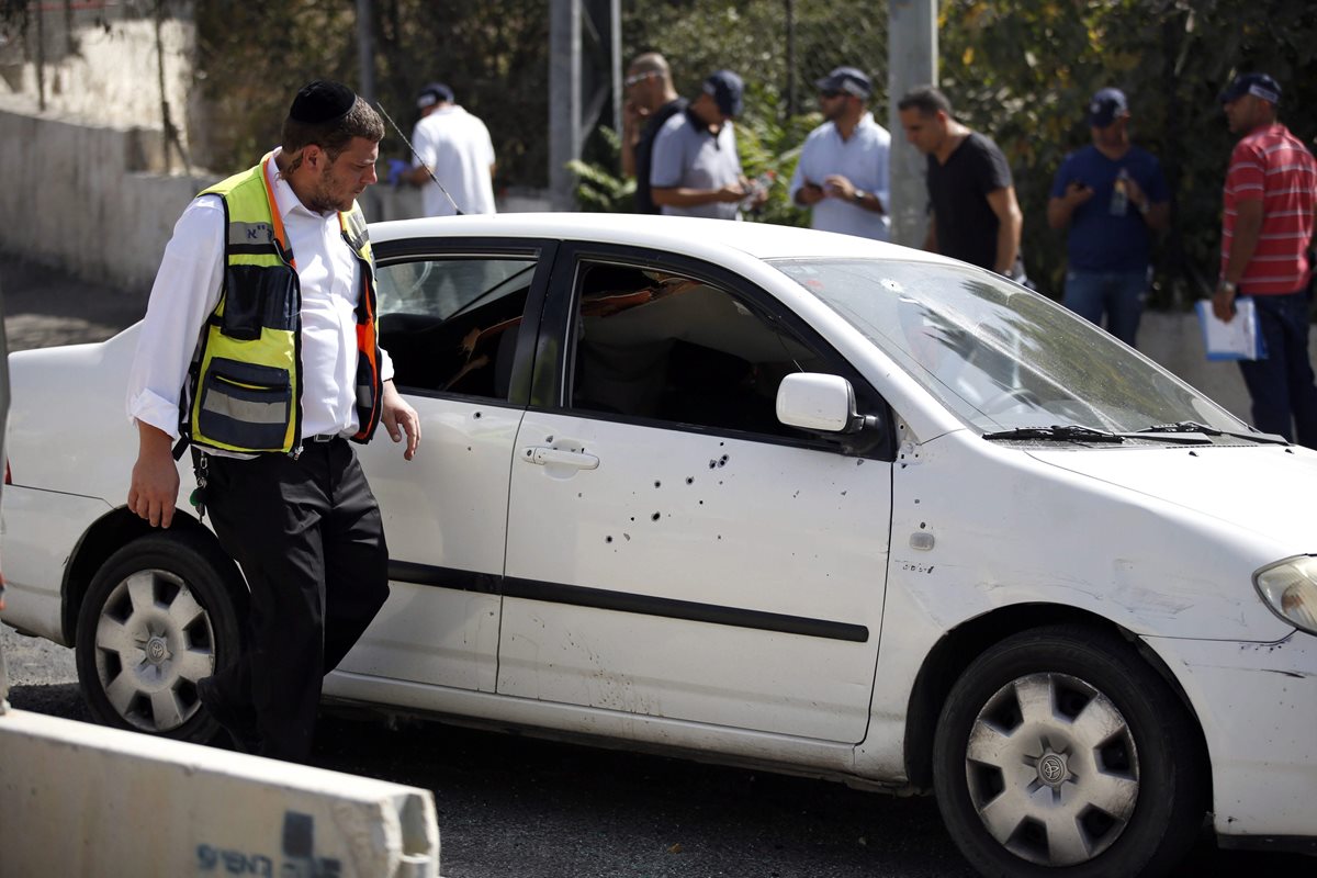 Un policía revisa uno de los vehículos que quedó en la escena de la balacera. (Foto Prensa Libre: EFE).