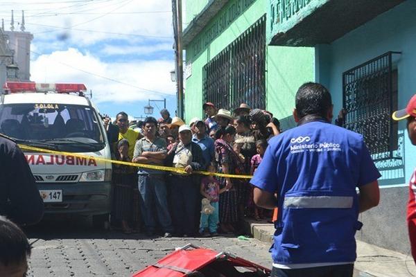 Curiosos observan el cadáver de Gerver  Arriola  Miranda, quien murió al caer de una acera, en Sololá. (Foto Prensa Libre: Édgar Sáenz)