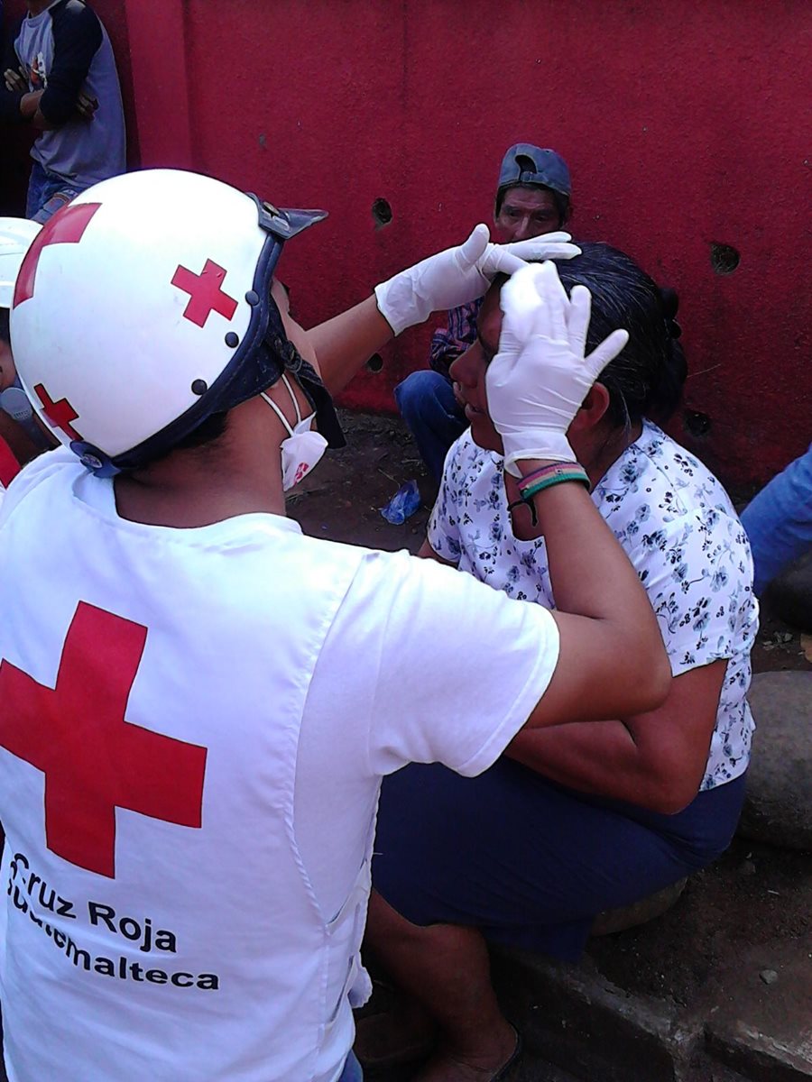 Socorrista de Cruz Roja da atención médica a mujer herida en enfrentamiento. (Foto Prensa Libre: Alexander Coyoy)