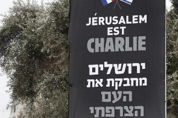 Unos judíos ortodoxos junto a un cartel que dice: "Jeruslaén también es Charlie". (Foto Prensa Libre: AFP)