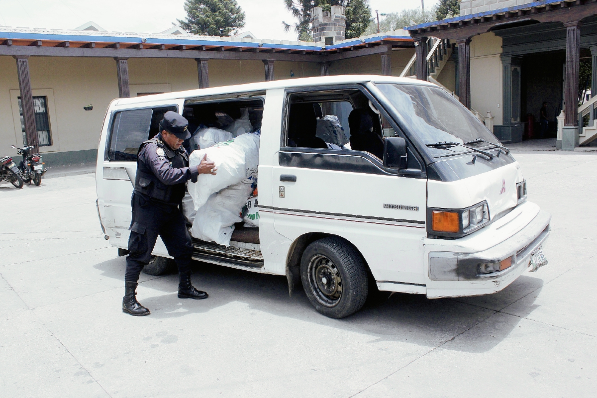 Agente de la PNC saca del microbús parte de la mercadería robada en San Martín Jilotepeque. (Foto Prensa Libre: Víctor Chamalé)