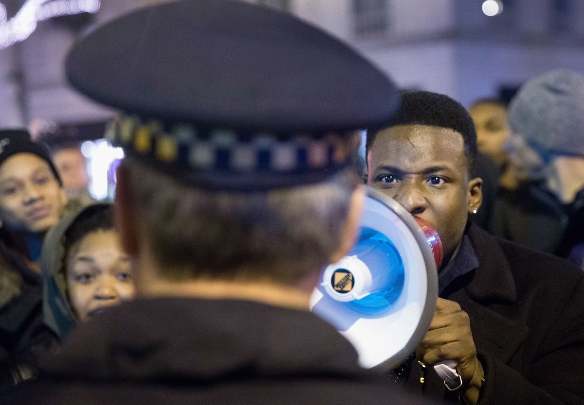 Descontentos gritan consignas a un policía en Chicago. (Foto Prensa Libre: AFP)