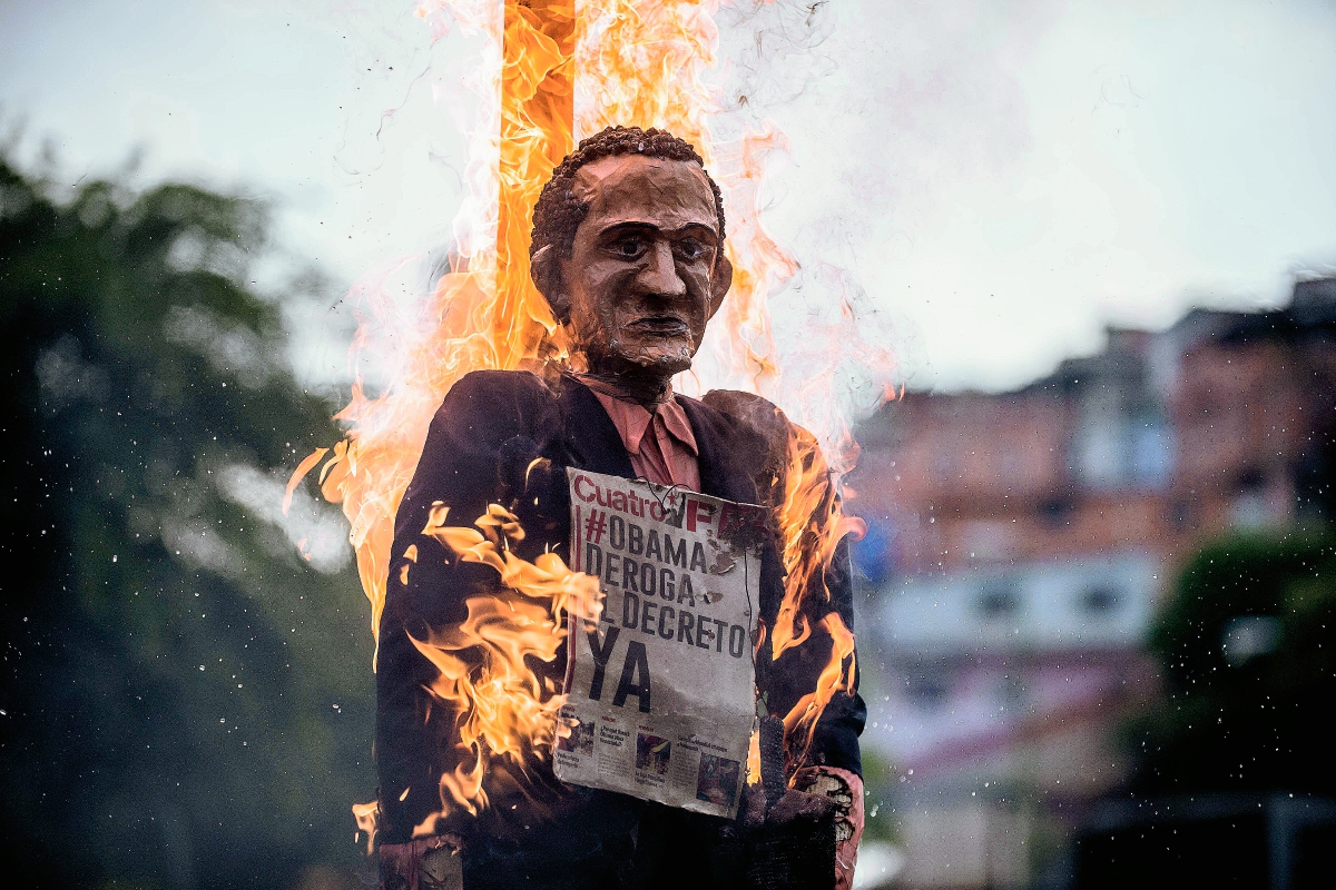Una piñata de Barack Obama, presidente de EE. UU., arde luego de ser quemado por simpatizantes del gobierno de Nicolás Maduro. (Foto Prensa Libre: AFP).
