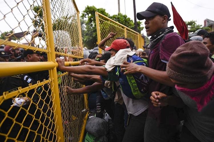 Momento en que las autoridades guatemaltecas intentan evitar el paso de hondureños hacia el puente internacional que divide el país con México. (Foto Prensa Libre: AFP)