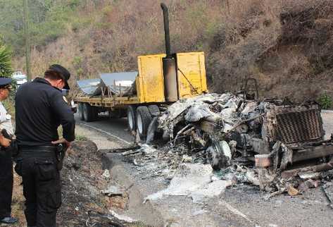 Agentes de la PNC observan  el área donde una turba incendió un tráiler que transportaba material para la minera San Rafael, en Santa Rosa.