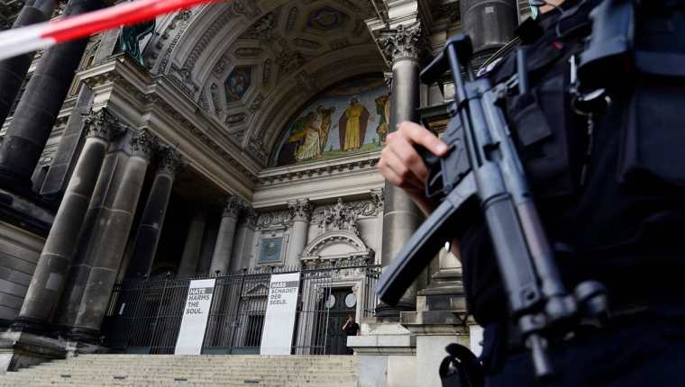 Un policía armado en la entrada principal de la catedral que luce acordonada. (Foto Prensa Libre: AFP)