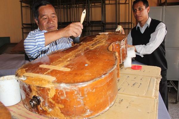 Francisco Otzoy Saj limpia el violonchelo, que sostiene William Tuyuc. (Foto Prensa Libre: José Rosales)