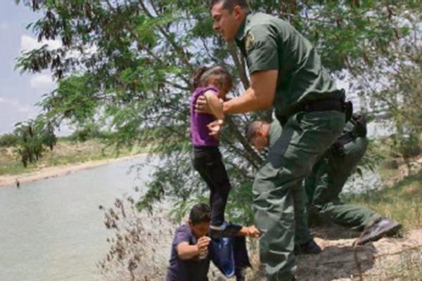 Una niña  es rescatada por agentes después al cruzar el río en la  frontera entre México y EE. UU. Cientos de migrantes indocumentados,  muchos de ellos niños, han llegado de manera ilegal a EE. UU., lo cual  ha causado una crisis humanitaria.