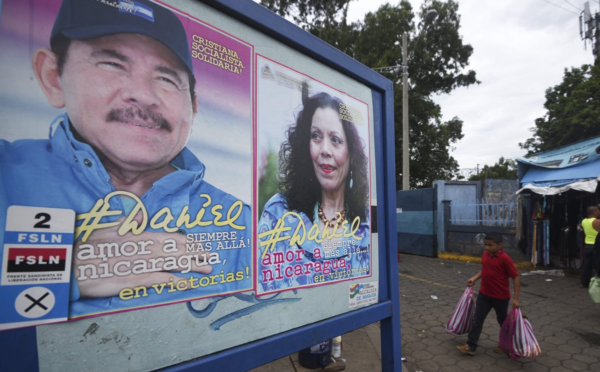 Un niño pasa frente a una valla del presidente Daniel Ortega y su esposa, Rosario Murillo. (Foto Prensa Libre: AFP)
