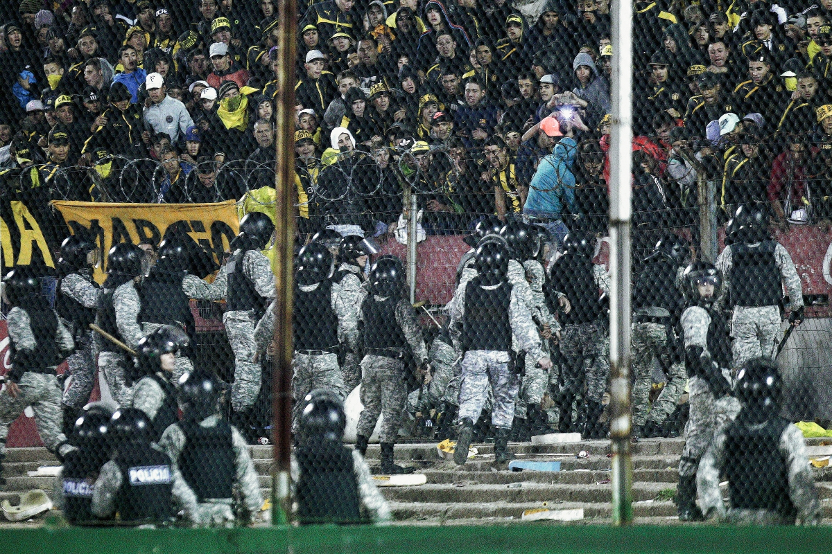 Policías se enfrentan a aficionados de Peñarol durante el partido por la final del torneo Clausura 2015 del futbol uruguayo, en el estadio Centenario de Montevideo. (Foto Prensa Libre: EFE)