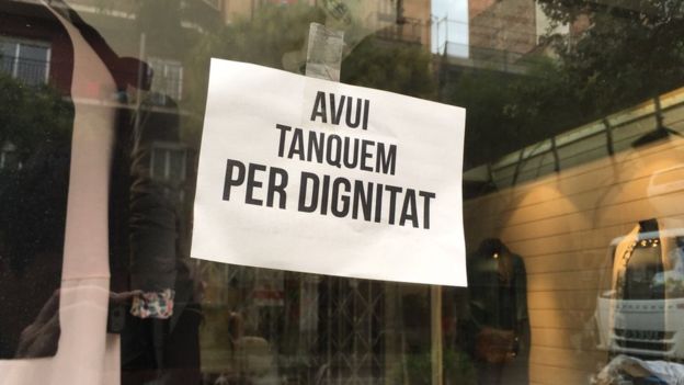 "Hoy cerramos por dignidad", se lee en un cartel en un comercio en Barcelona, en apoyo al paro general. ENRIC BOTELLA/BBC MUNDO