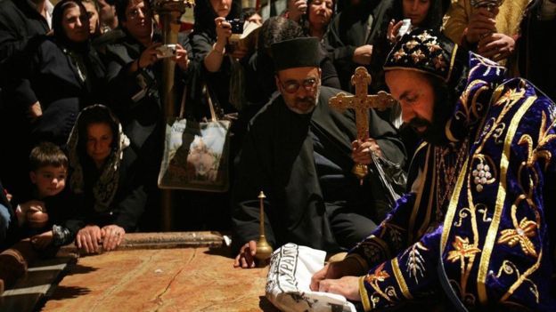 Un arzobispo sirio, que representa a una de las sectas que usan la iglesia, reza sobre la Piedra de la Deposición. GETTY IMAGES