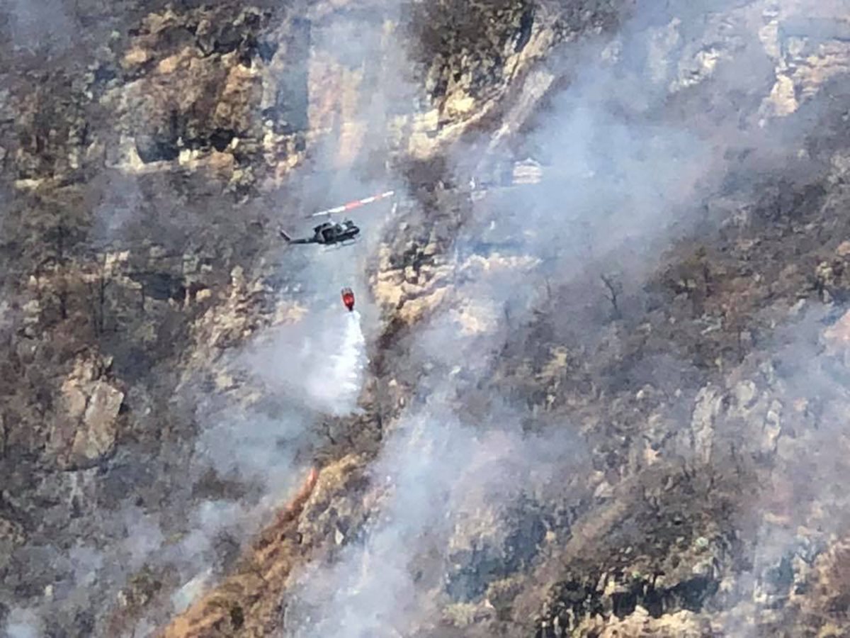 Un helicóptero vierte agua sobre un foco de incendio forestal en el volcán San Pedro. (Foto Prensa Libre: Ángel Julajuj)