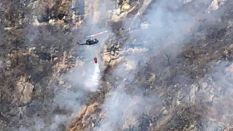 Un helicóptero vierte agua sobre un foco de incendio forestal en el volcán San Pedro. (Foto Prensa Libre: Ángel Julajuj)