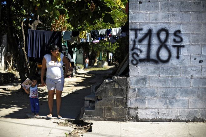 Mujer y niño junto a un grafiti del Barrio 18 en la colonia Valle del Sol en Apopa, El Salvador. (Foto: José Cabezas / Getty Images)