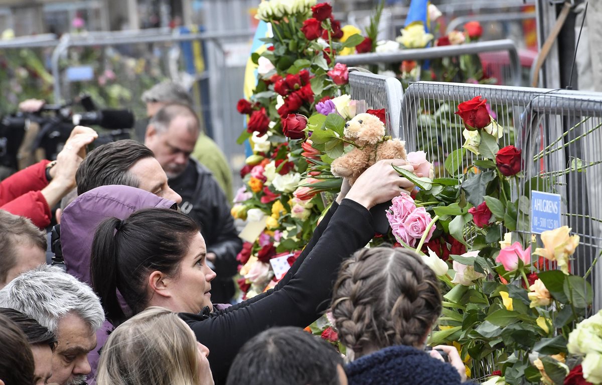 Varias personas colocan flores en la escena del crimen en el centro de Estocolmo.(Foto Prensa Libre:EFE).