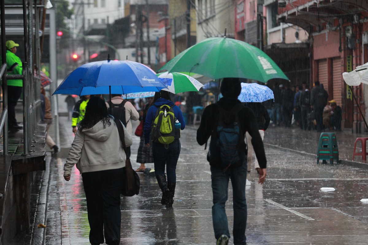Guatemaltecos se cubren de la lluvia mientras caminan por la zona 1 capitalina. (Foto Prensa Libre: Hemeroteca PL)